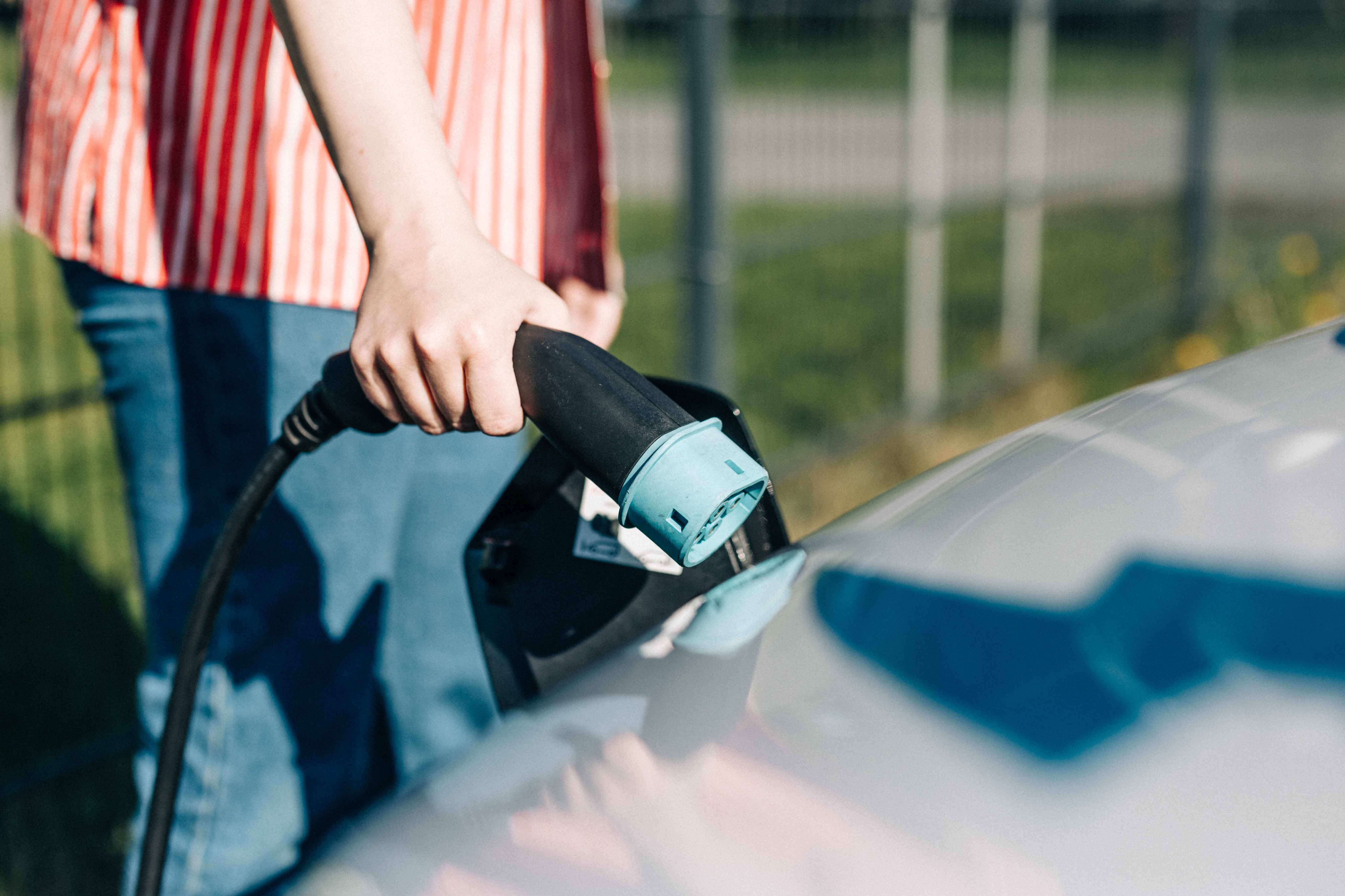 Henkilö lataamassa sähköautoa