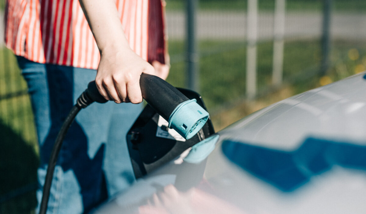 Henkilö lataamassa sähköautoa